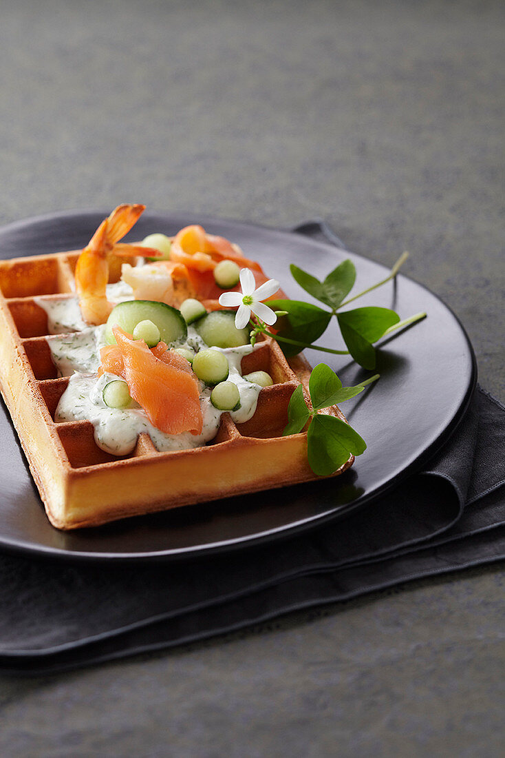 A waffle with prawns, salmon and creamy cucumber