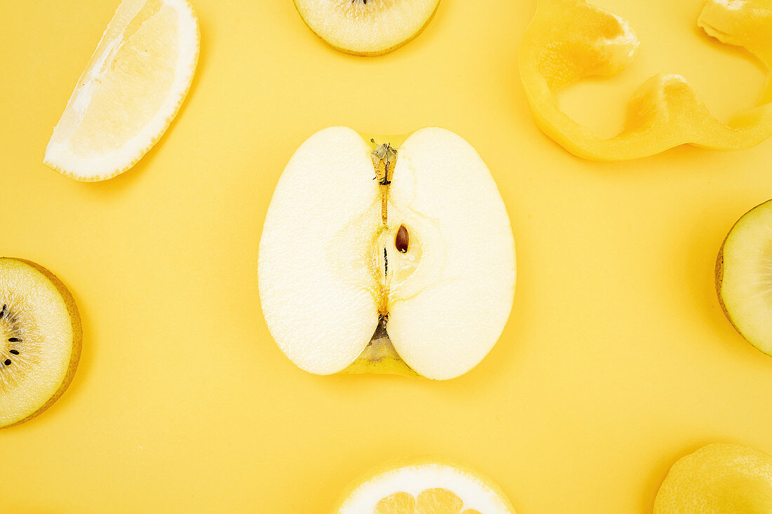 Various fresh fruits and vegetables arranged on yellow background