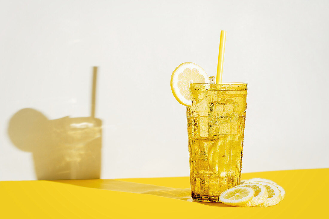 Glass of fresh beverage with lemons placed on table