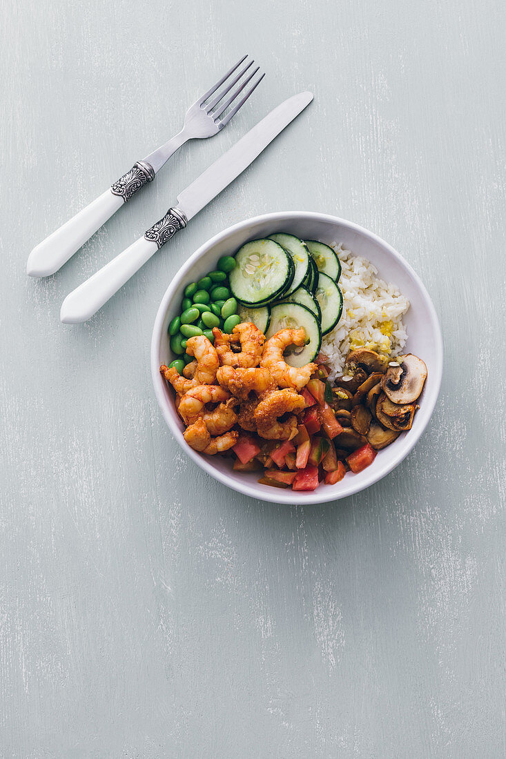 Poke bowl with rice and cucumber with beans and mushrooms topped with shrimps
