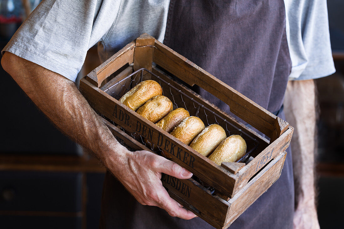 Male baker with wooden box full of freshly baked doughnuts
