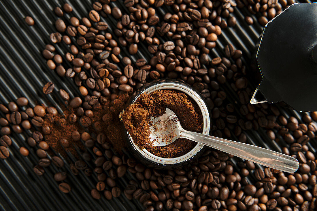 Gemahlener Kaffee in Espressokanne und verstreute Kaffeebohnen