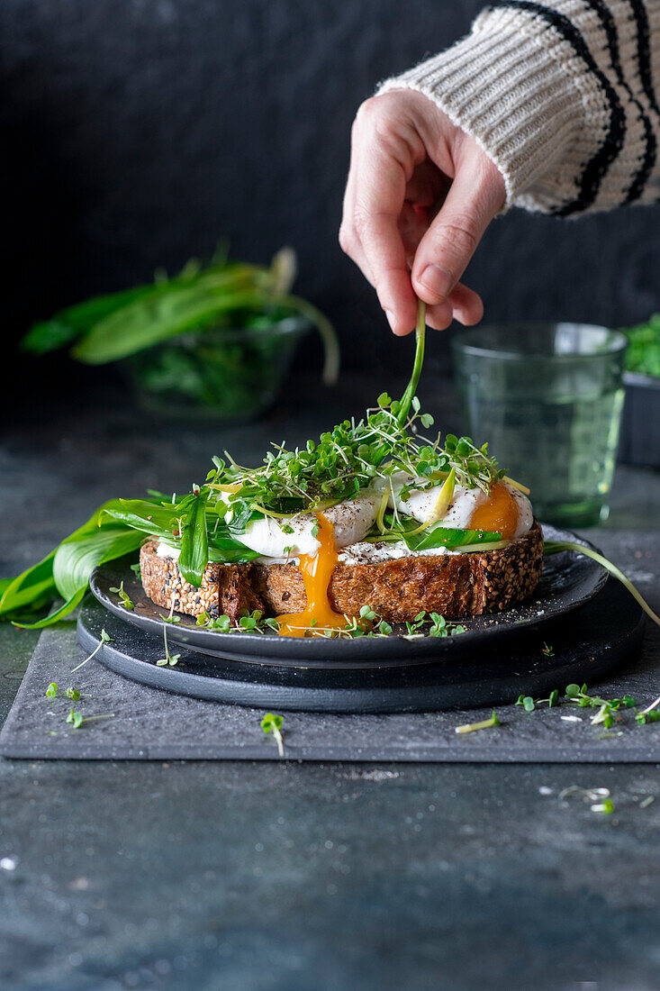 Open faced sandwich topped with wild garlic and an egg with a broken yolk