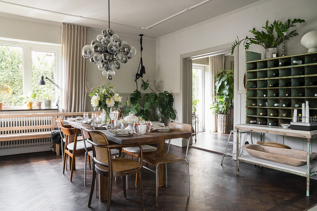 Solid wood table with flea market chairs, pendant lamp with glass spheres above in the dining room