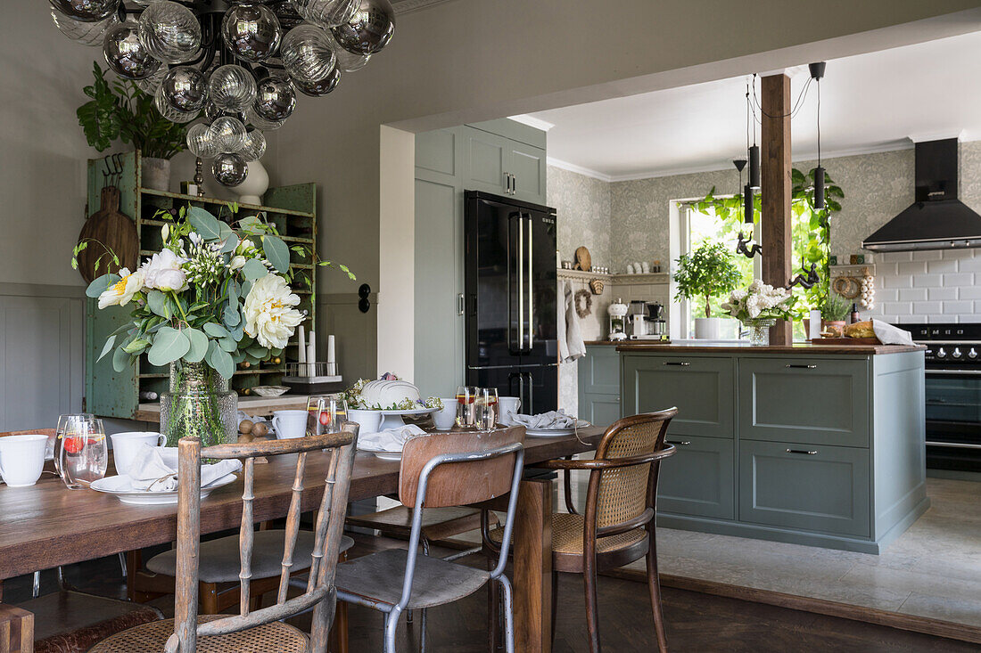 Solid wood table with flea market chairs, pendant lamp with glass spheres above in the dining room