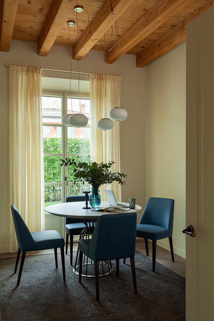 Blue leather chairs around a round table in a room with a woodbeamed ceiling