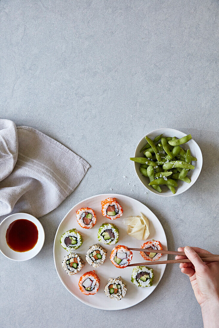 Mixed sushi platter with chopsticks and edamame