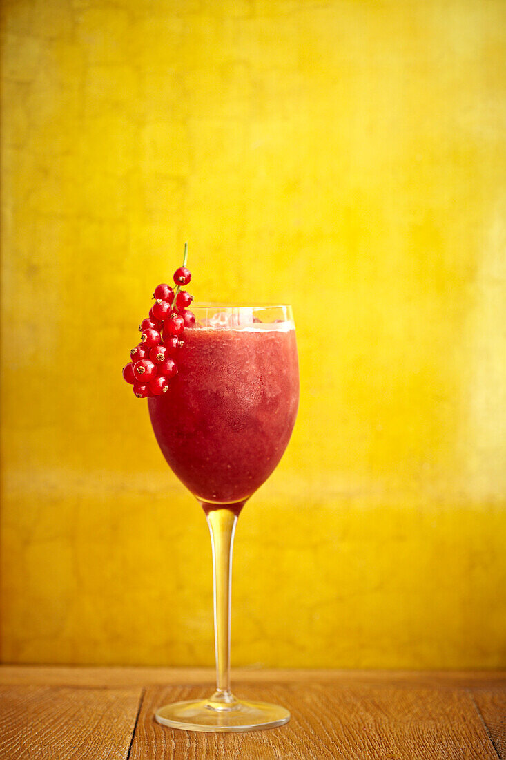 A fruity red cocktail against a yellow background