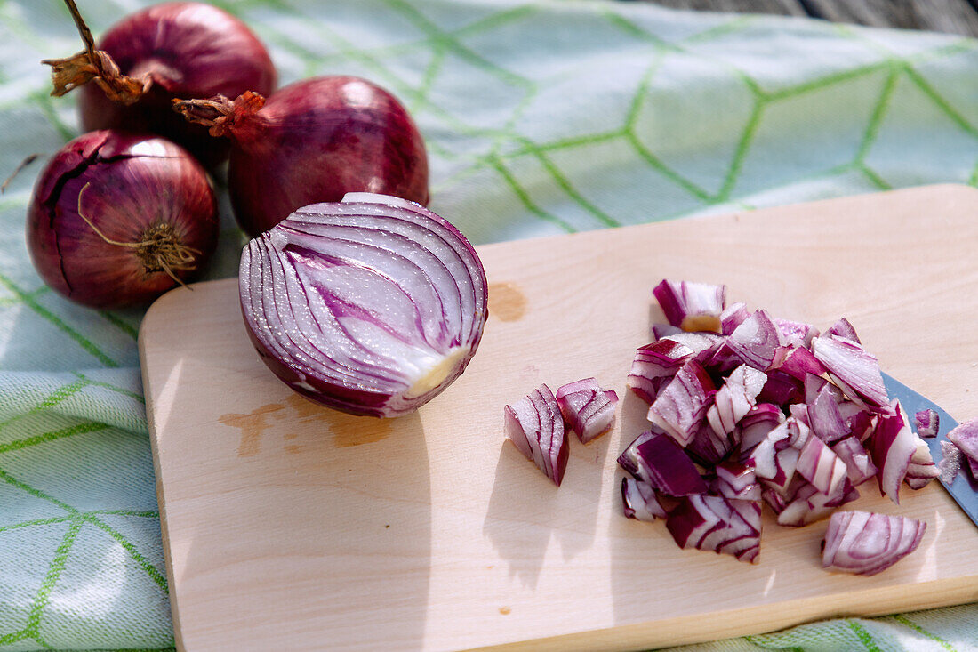 Red onions, halved and diced, on a wooden board with a small knife