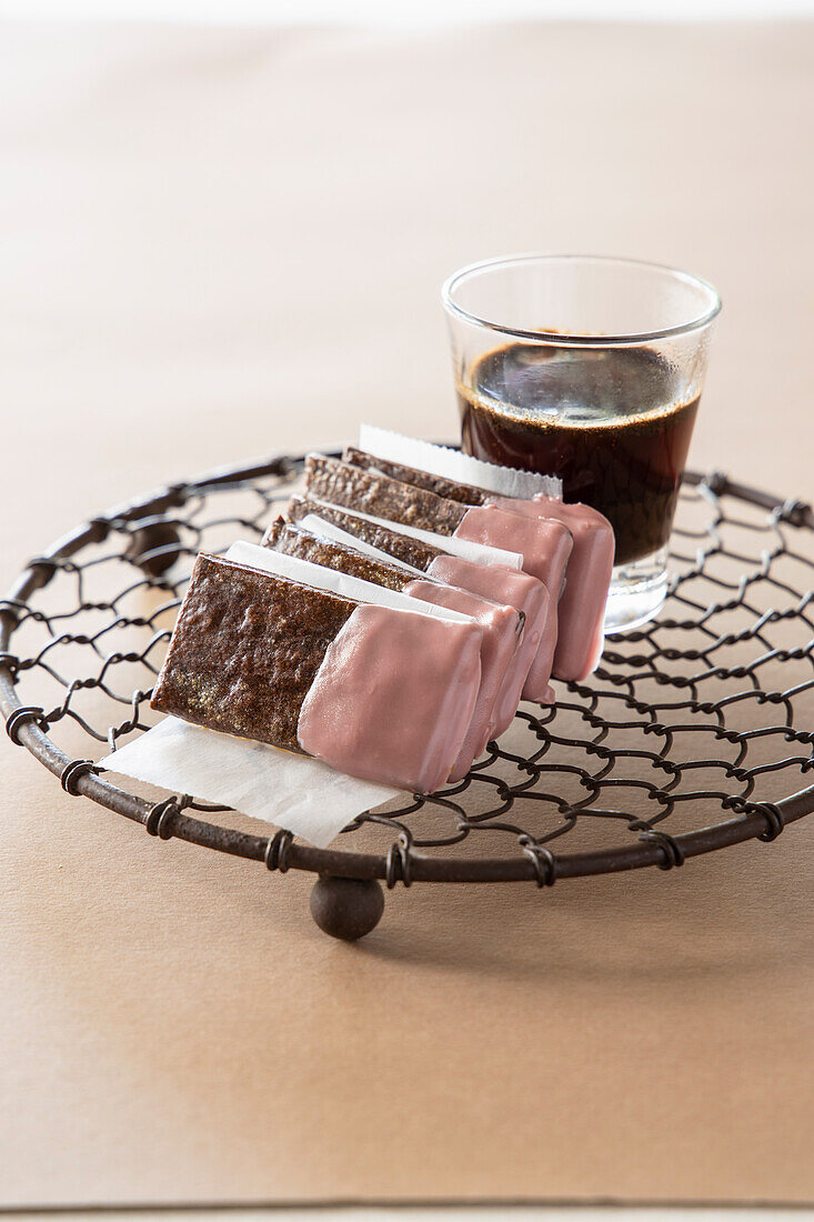 Schokoladenkekse mit rosa Glasur dazu ein Glas Kaffee