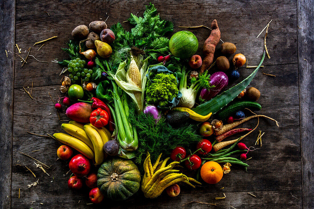 Heimische und exotische Früchte und Gemüse auf rustikalem Holztisch
