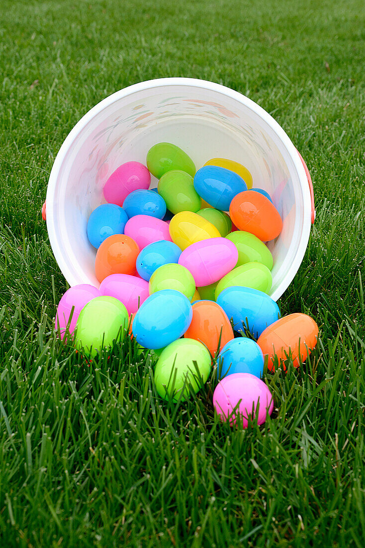 Colorful Plastic Easter Eggs spilling out of Bucket on Green Grass