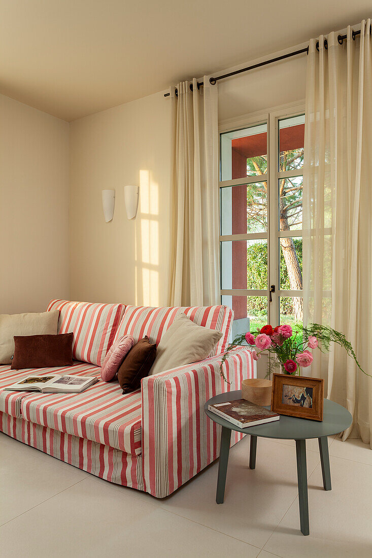 Sofa mit gestreiftem Bezug und Beistelltisch im Wohnzimmer mit cremefarbenen Wänden