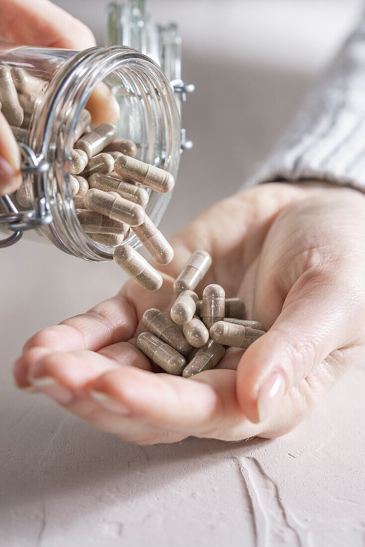 Supplements being poured from a jar into a hand
