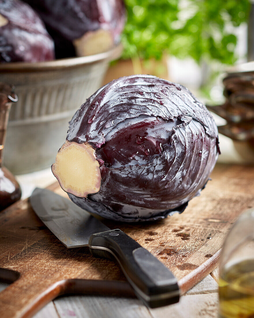 Red cabbage with a knife on a wooden cutting board