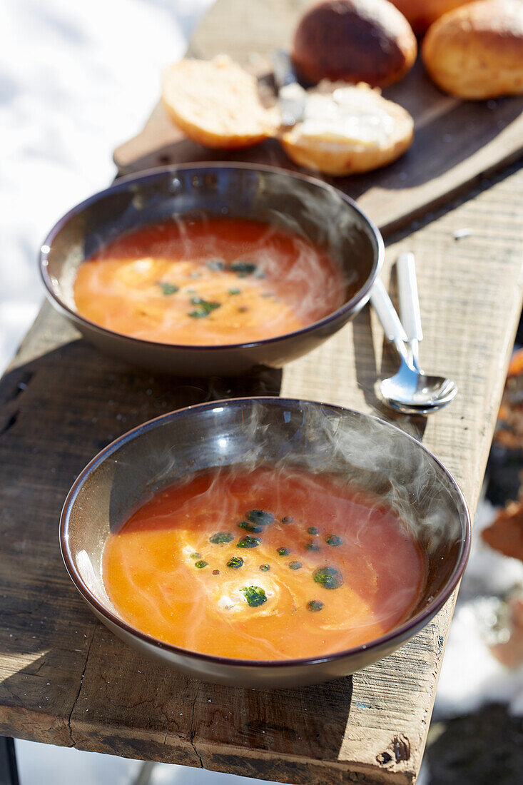 Dampfende Tomatensuppe auf Tisch im winterlichen Garten