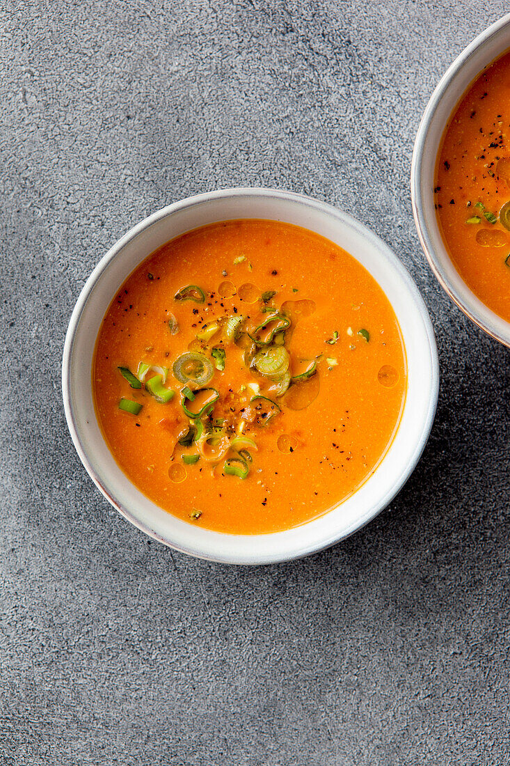 Cherry tomato soup garnished with pistachios and finely chopped spring onions