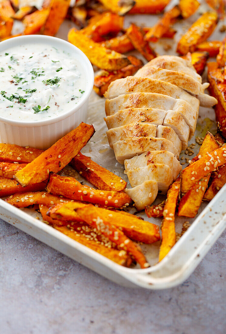 Pumpkin fries with chicken served on a tray with tahini dip