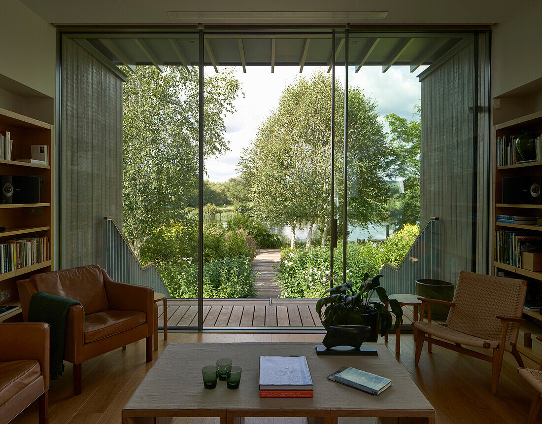 Wohnzimmer mit Bücherregalen und Sitzmöbeln, Blick in den Garten