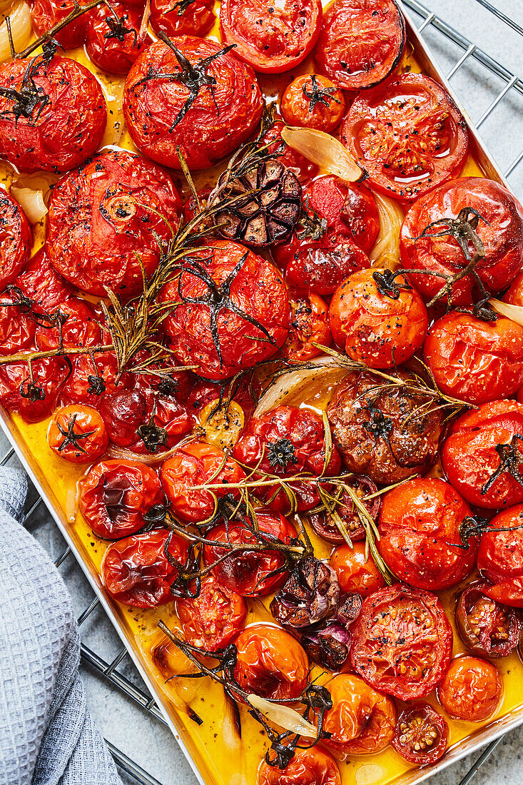 Geröstete Tomatensauce aus dem Ofen zubereiten - Tomaten mit Knoblauch und Kräutern auf Ofenblech