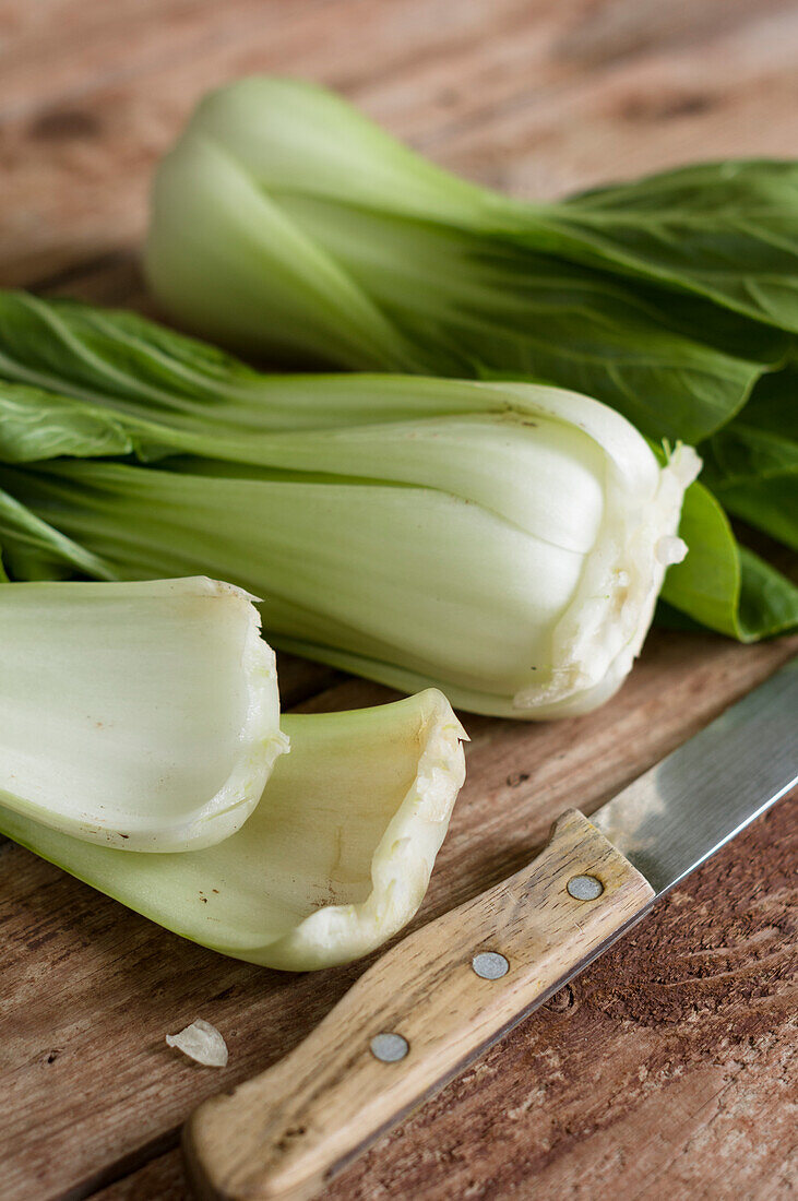 Bok choy with a knife on a wooden cutting board