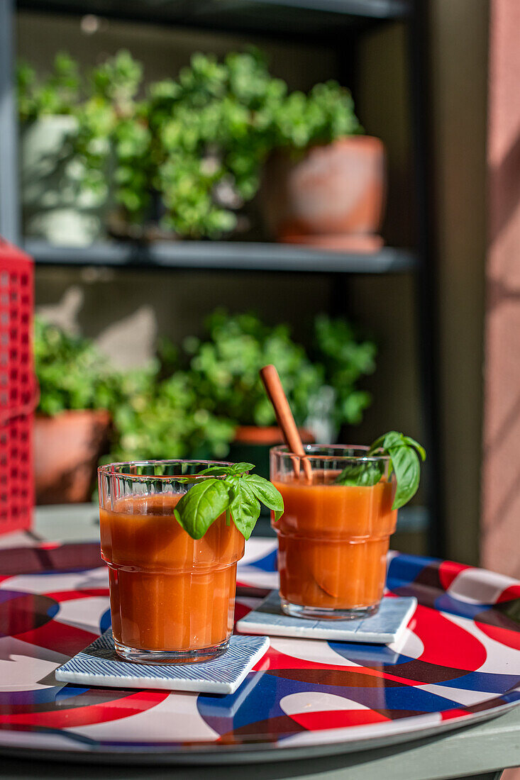 Gazpacho-Suppe serviert mit Basilikum in Gläsern auf Tablett