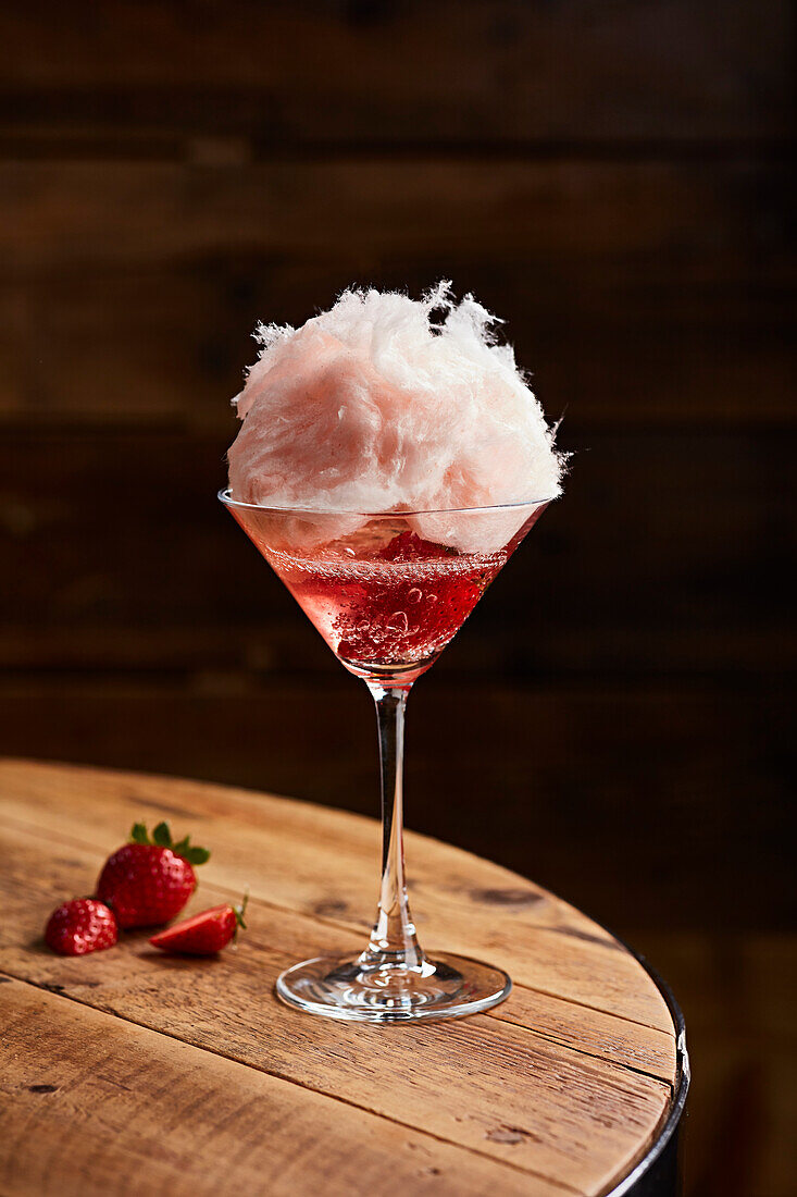 A strawberry cocktail garnished with candy floss