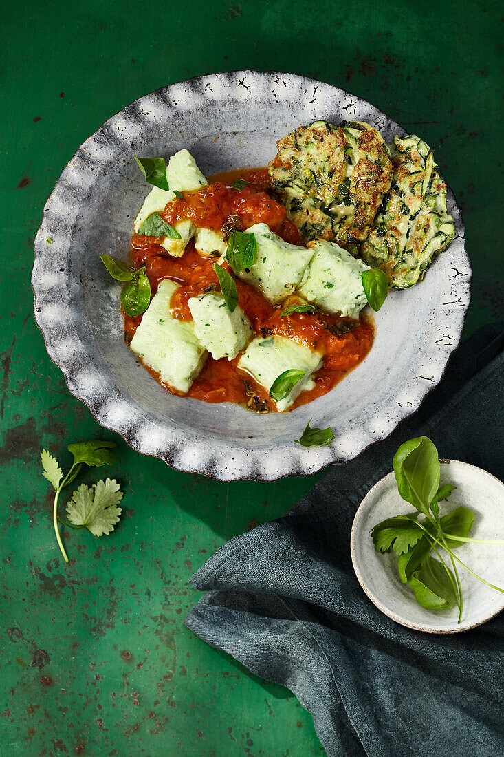 Green gnocchi with courgette pancakes on roasted tomato sauce