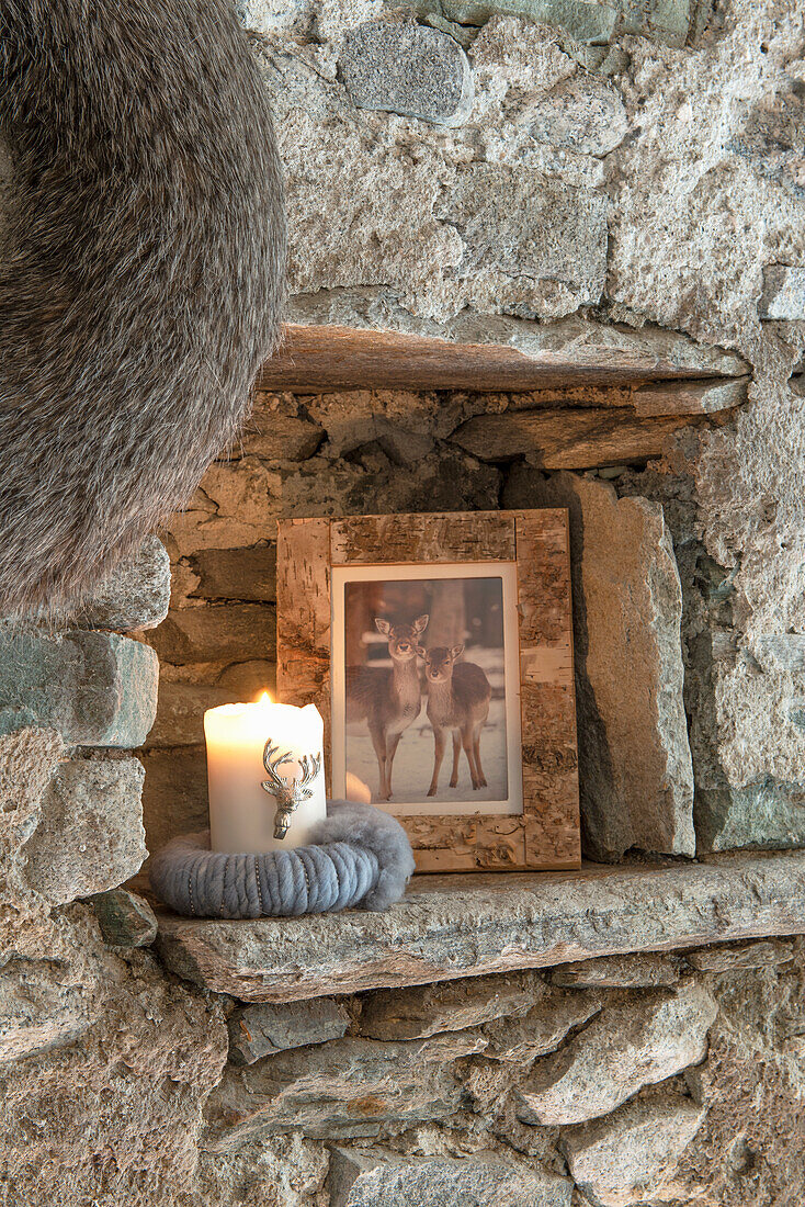 Gerahmtes schwarz-weißes Foto und Kerze in Naturstein-Wandnische