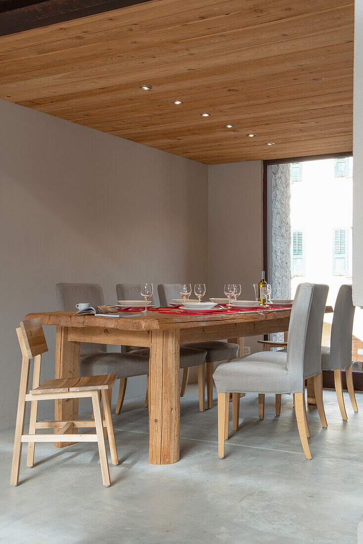 Solid wood dining table with upholstered chairs on concrete floor