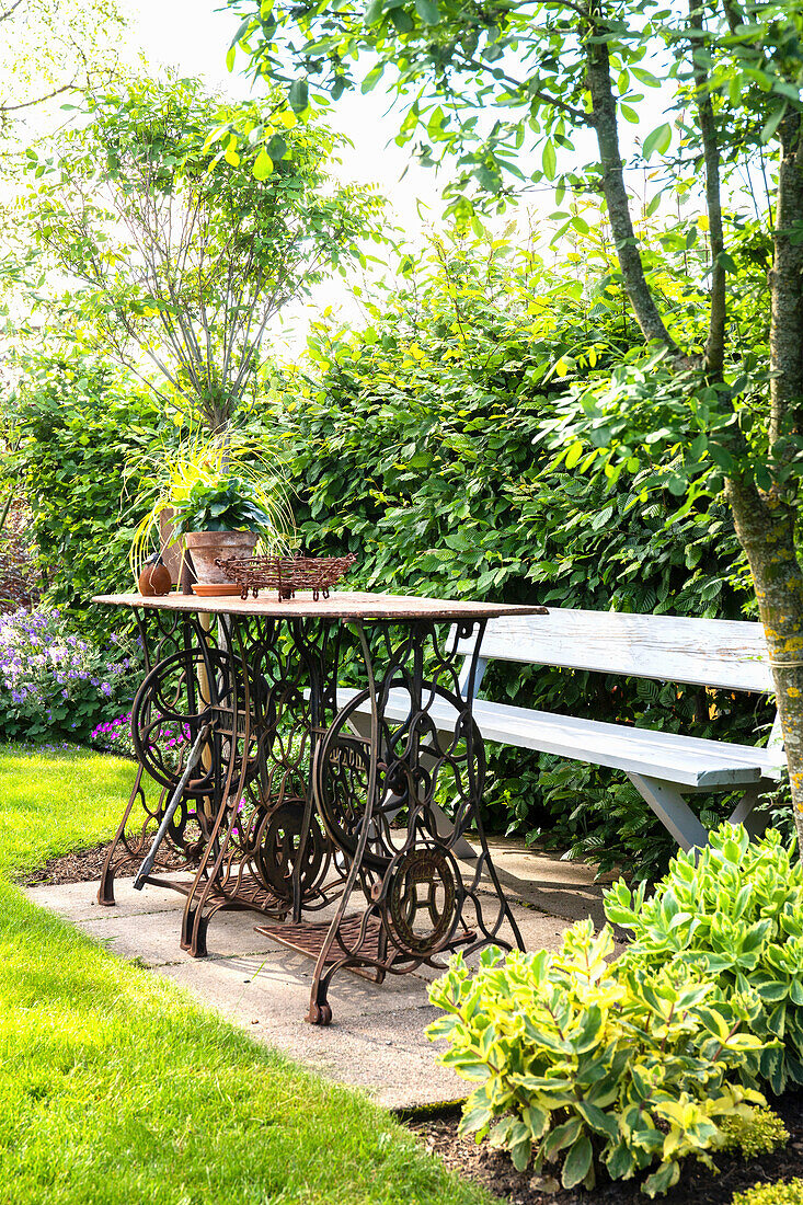 Gemütlicher Sitzplatz mit Gartentisch aus zwei Nähmaschinen und Bank