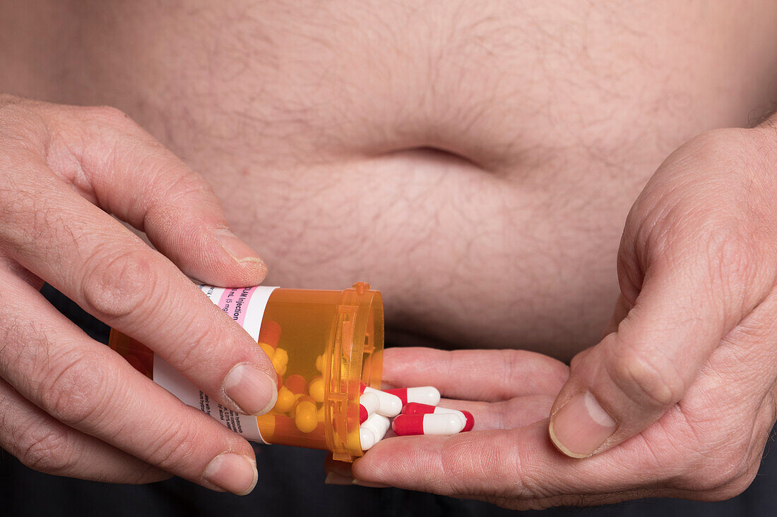 Overweight man taking medication, conceptual image