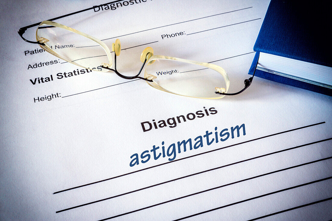 Astigmatism diagnosis on a form next to glasses