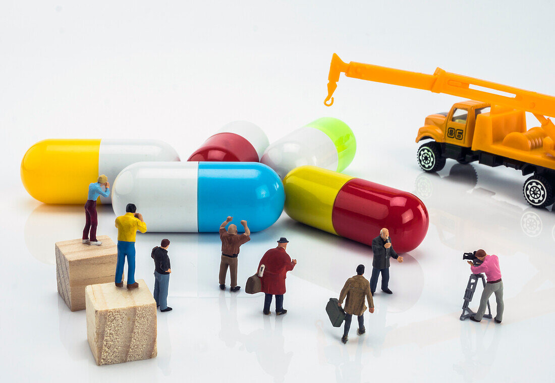 Miniature people figures next to large capsules