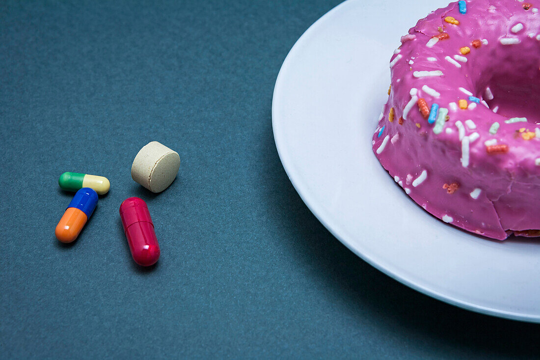 Diabetes medication next to a cake, conceptual image