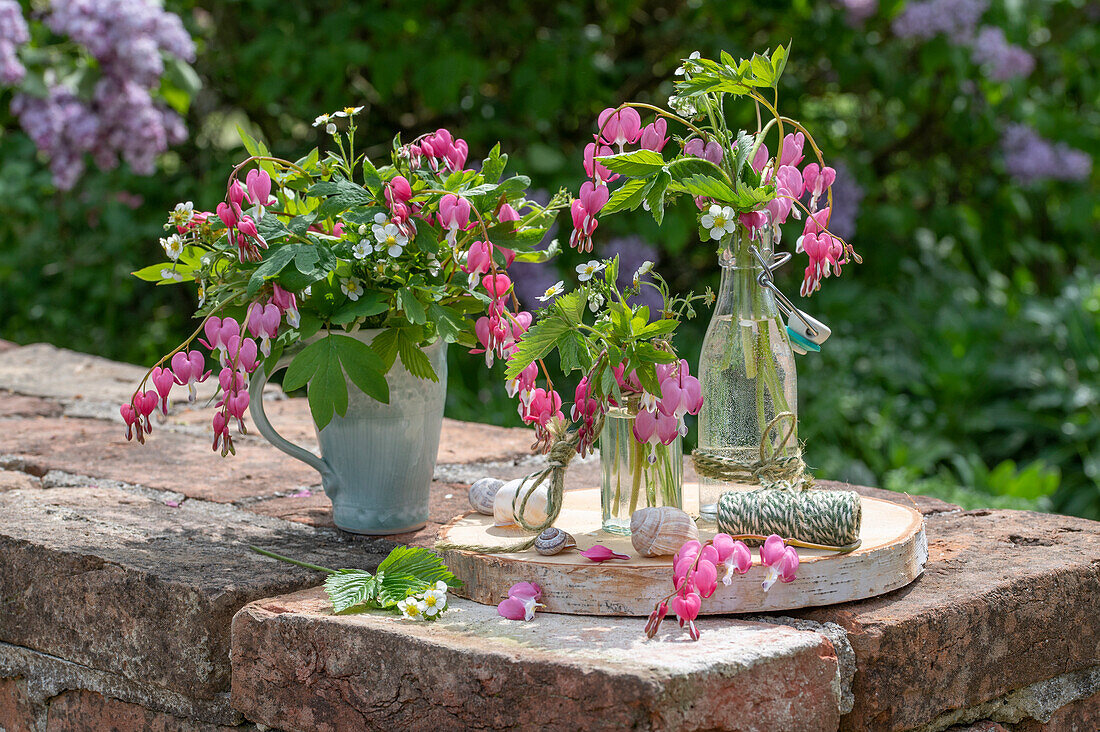 Blumenstrauß Tränendes Herz (Dicentra Spectabilis) und Erdbeerblüten in Vasen