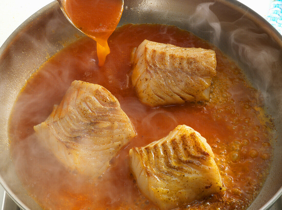 Fish fillets in tomato sauce being made
