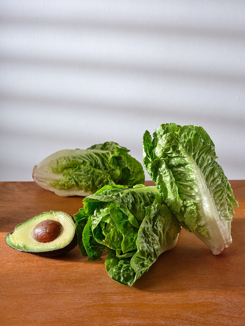 Romaine lettuce and half an avocado on a wooden counter