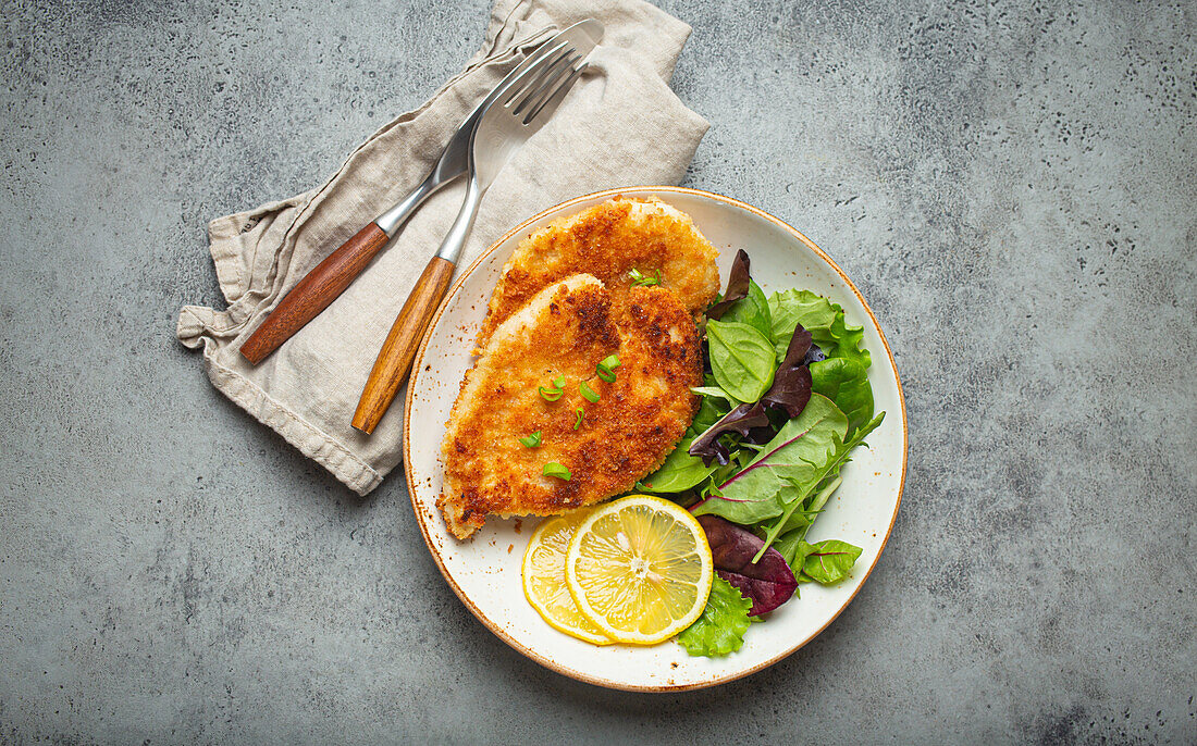 Knuspriges Hähnchenfilet in Panko-Panade mit grünem Salat und Zitrone