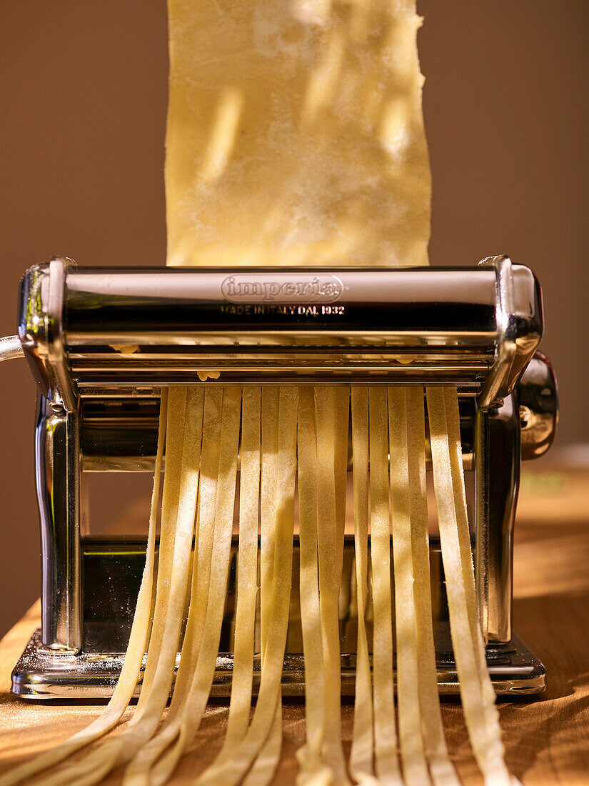 Tagliatelle being made with a pasta machine
