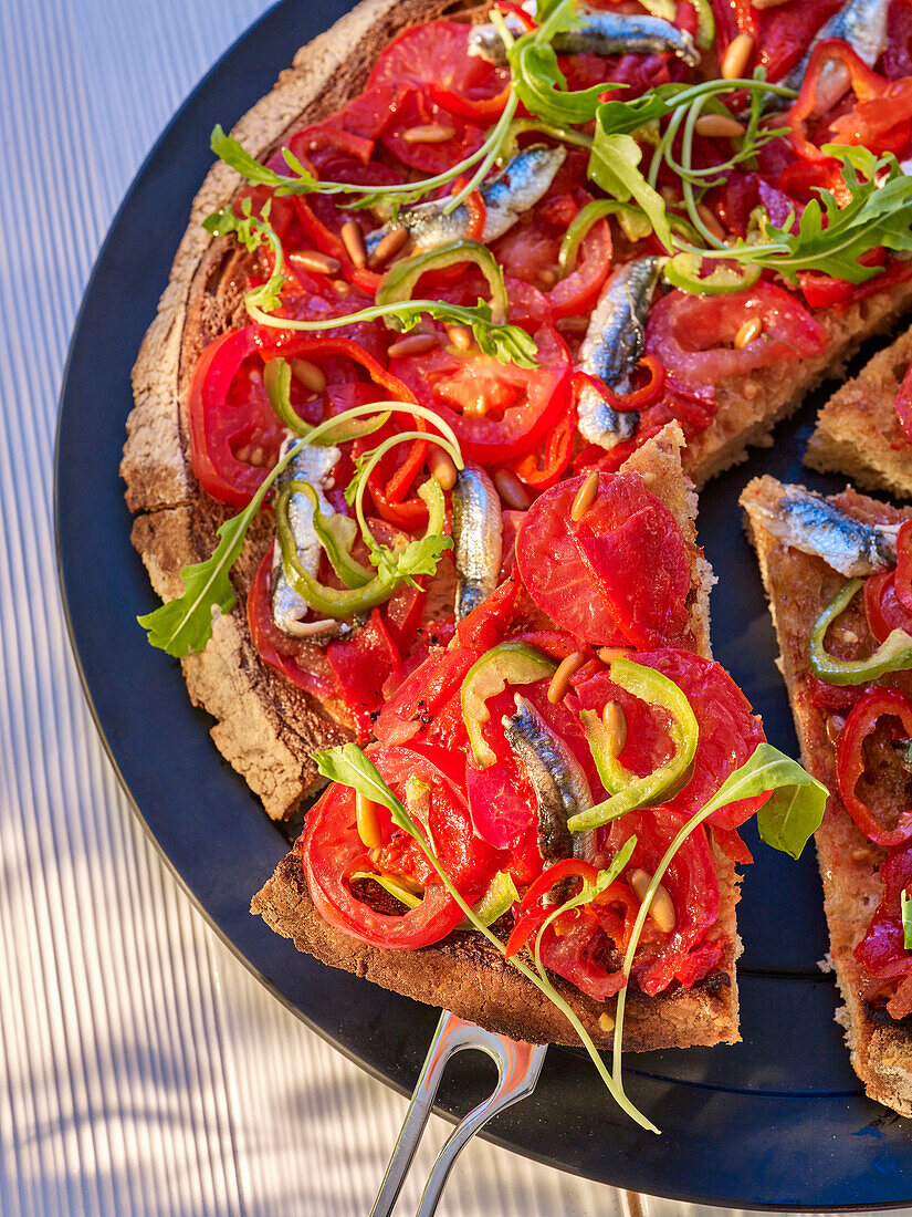 Pizza with tomatoes, anchovies and rocket salad