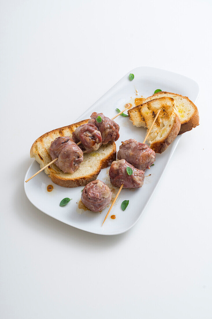 Pork rolls on skewers with mortadella and scamorza