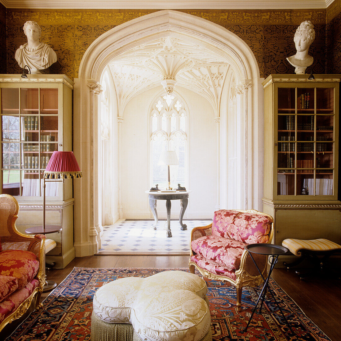 Shamrock-shaped stool upholstered in Lelievre silk in a living room with original Gothic arch and black and gold wallpaper