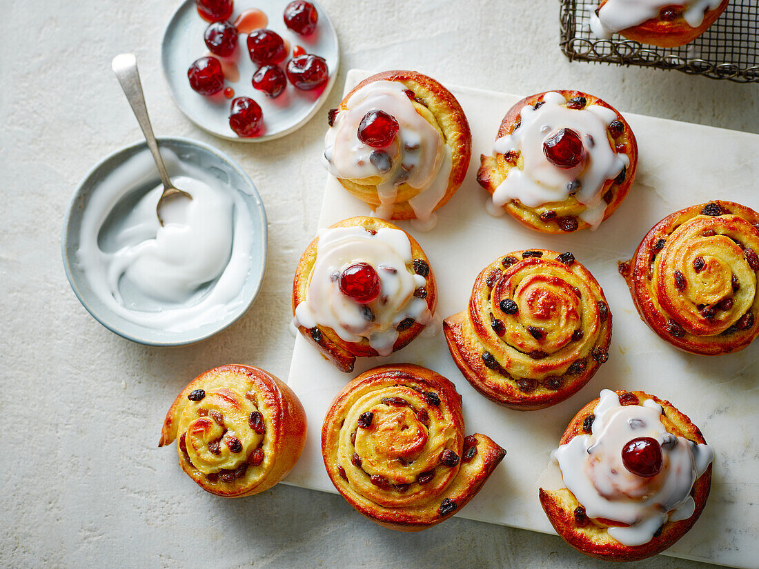 Belgian buns (yeast buns with golden raisins, fondant icing, and cherry topping)