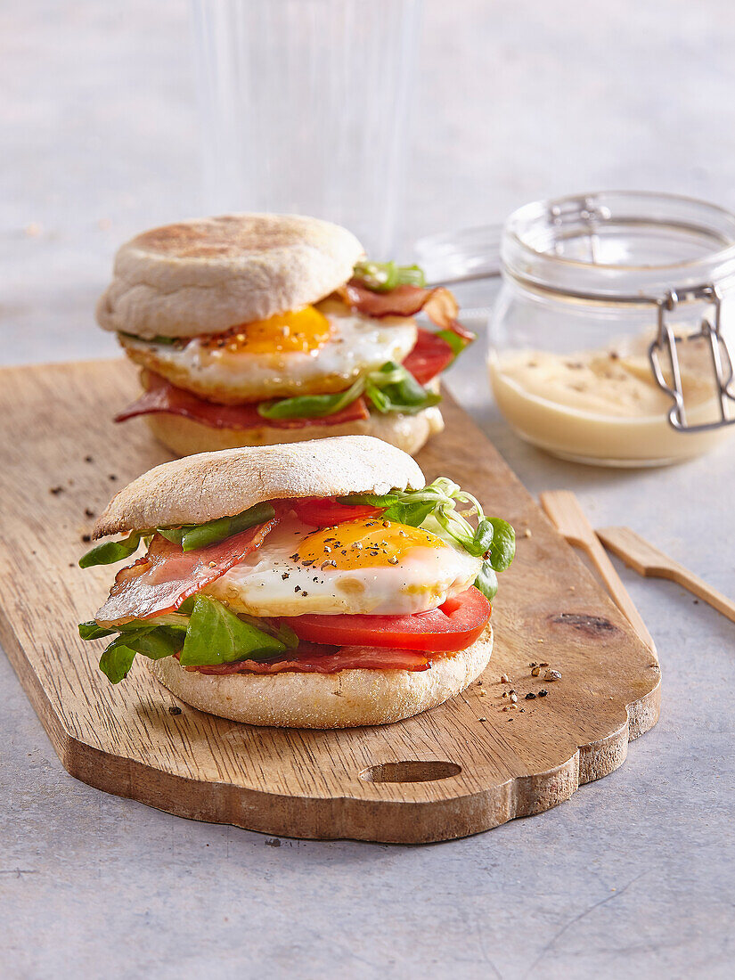 Frühstückssandwich mit English Muffin, Tomate, Speck und Spiegelei