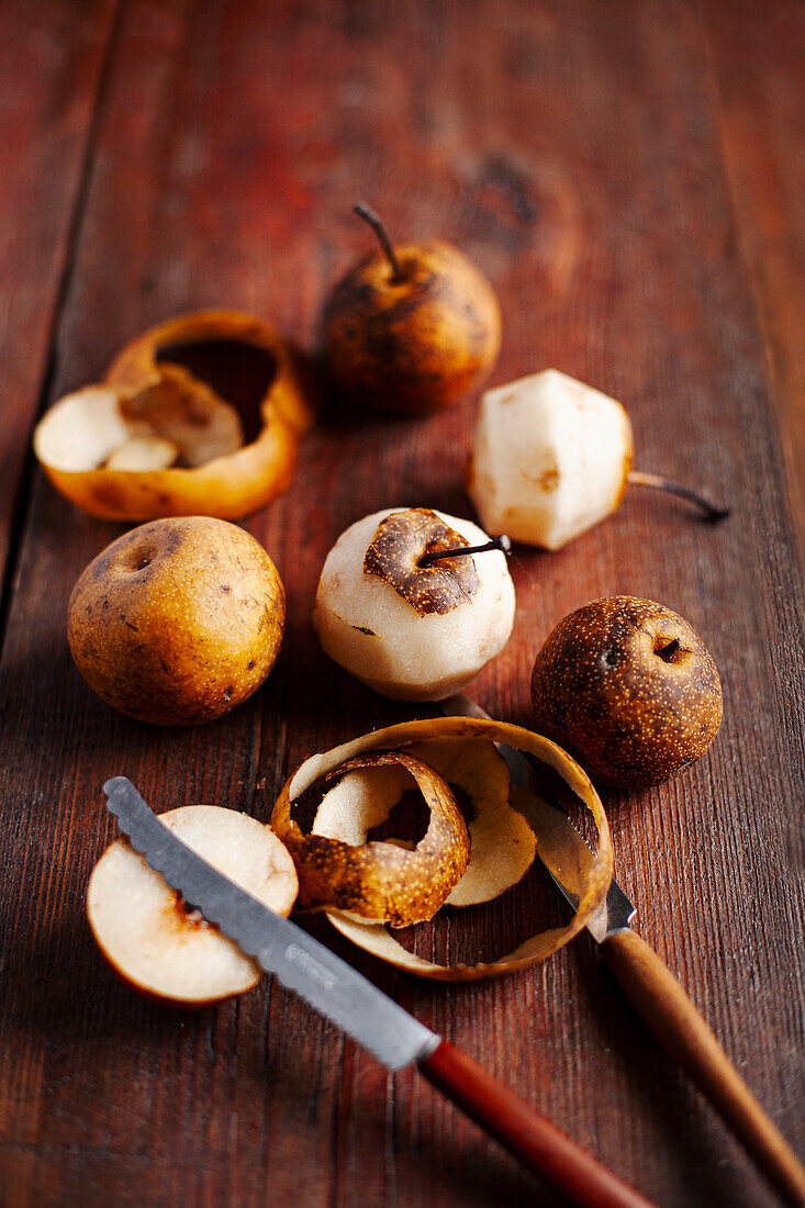 Nashi pears, partly peeled on wooden base