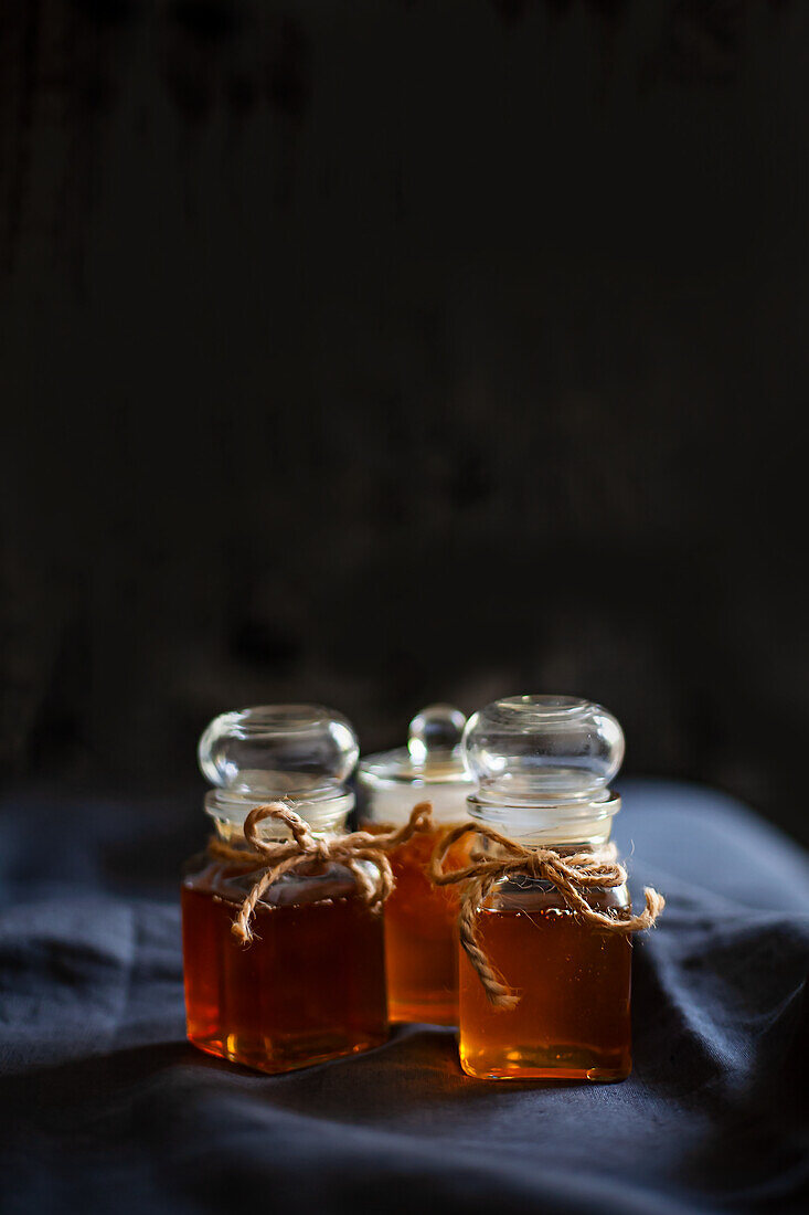 Honig in Gläsern vor schwarzem Hintergrund