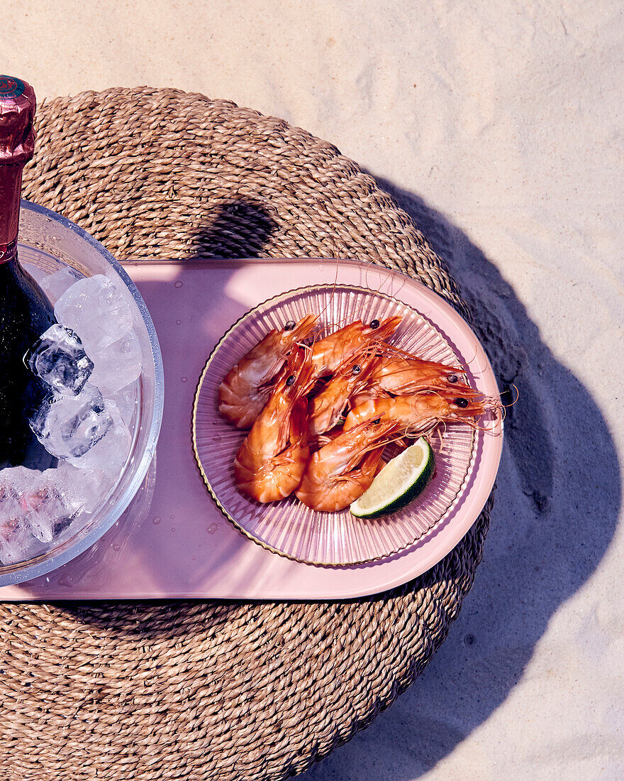 Garnelen und Champagnerflasche auf Eis am Strand