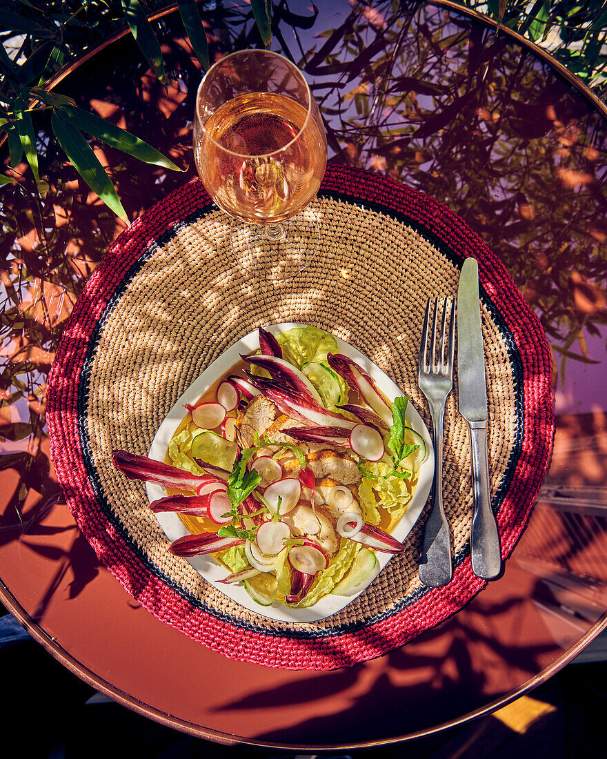 Caesar Salad mit rotem Chicoree und Radieschen auf Tisch im Freien