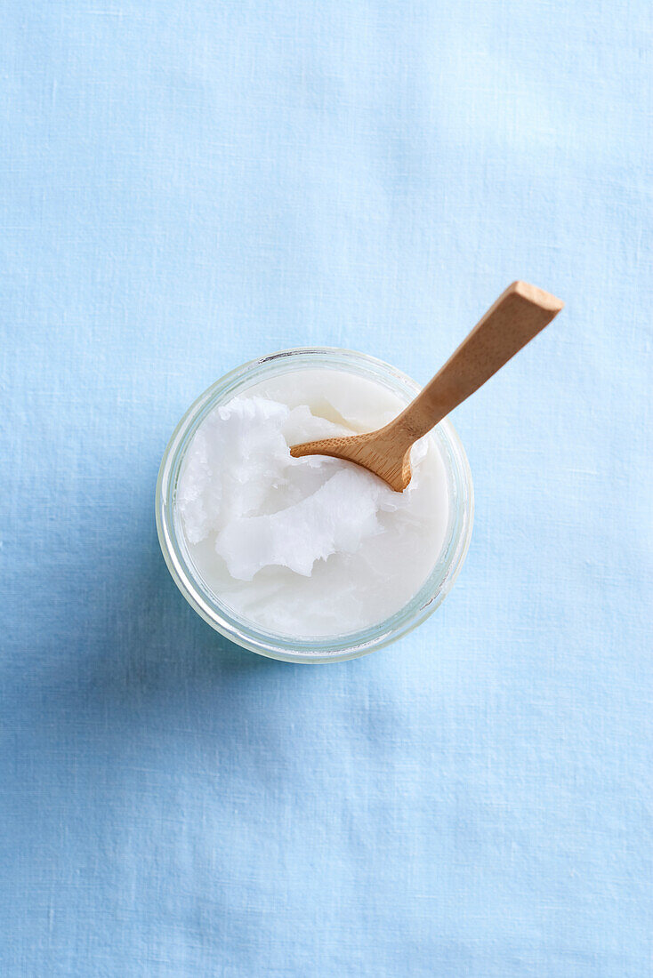 Coconut oil with wooden spoon in a jar